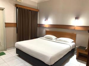 a bedroom with a large bed with white sheets at Hotel Caravan in Jakarta