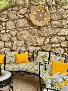 a bench with yellow pillows and a stone wall at Hotel Imperial in Dhërmi