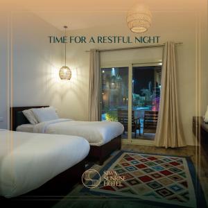una habitación con 2 camas y un cartel que dice hora para una noche residual en Siwa Sunrise Hotel en Siwa