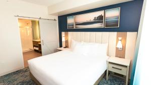 a bedroom with a white bed and a blue wall at Holiday Inn Club Vacations Myrtle Beach Oceanfront in Myrtle Beach