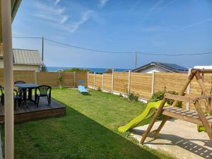 einen Hinterhof mit einem Holzzaun und einem Spielplatz in der Unterkunft La maison entre deux plages,vue sur mer classée 4 étoiles in Criel-sur-Mer