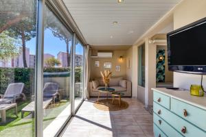 un salon avec des portes coulissantes en verre et une télévision dans l'établissement Appartement rez de jardin climatisé, au Cap d'Agde