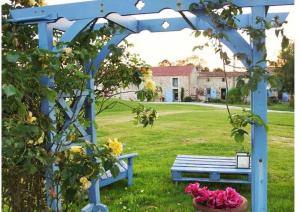 eine blaue Bank im Gras mit einem Garten in der Unterkunft Le Clos du Gâts Gîte de charme en Vendée à 15 mn du Parc du Puy duFou in La Gaubretière