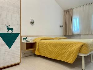 sypialnia z łóżkiem z żółtym kocem w obiekcie Hotel Giardino w mieście Breno