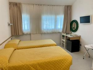 una camera d'albergo con due letti e uno specchio di Hotel Giardino a Breno