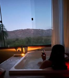 una persona sentada en una bañera con una copa de vino en Pousada Belvedere da Serra, en Serra do Cipo