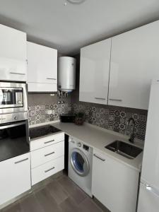 - une cuisine avec des placards blancs et un lave-linge dans l'établissement Arenales Beach Boutique Apartment, à Arenales del Sol