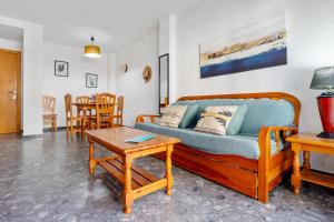 uma sala de estar com um sofá azul e uma mesa em Pineda 318 em La Pineda