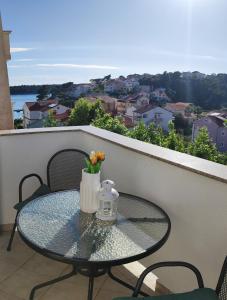 a glass table with a vase of flowers on a balcony at Rooms and Apartments Riviera in Rab