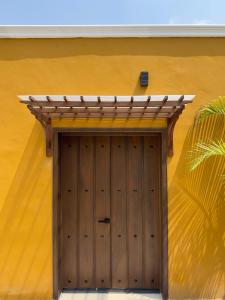 a wooden garage door with a wooden roof on a yellow wall at Viveza - Downtown in Campeche