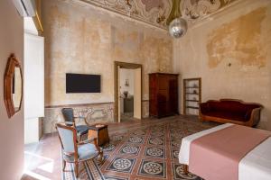 a bedroom with a bed and a tv on the wall at Palazzo Sant'Isidoro by DomuSicily in Palermo