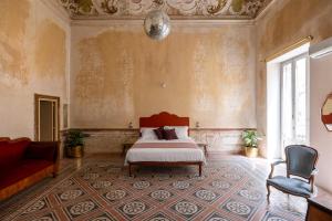 a bedroom with a bed and a chair and a couch at Palazzo Sant'Isidoro by DomuSicily in Palermo