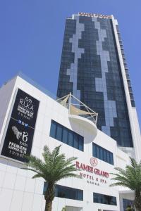 a tall building with palm trees in front of it at Ramee Grand Hotel And Spa in Manama