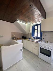 a kitchen with white appliances and a wooden ceiling at Oros Eros in Hydra