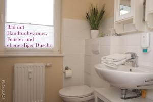 uma casa de banho branca com um lavatório e um WC em Ferienwohnung Strandgut em Prerow