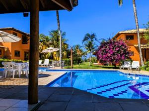 a pool at a resort with chairs and trees at Residence Maria Vittoria Praia Arraial in Arraial d'Ajuda