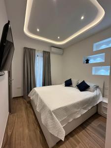 a bedroom with a white bed and a television at Acacia Avenue Apartments in Is-Swieqi