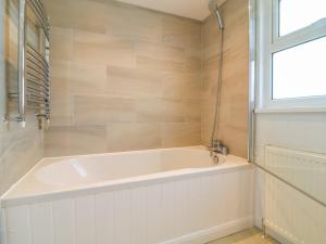 Una bañera blanca en un baño con ventana. en Alpha, en Wadebridge 34 fotos más