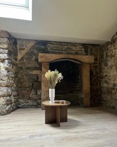 a room with a table with a vase of flowers on it at Le Moulin de Blanchelande in Neufmesnil