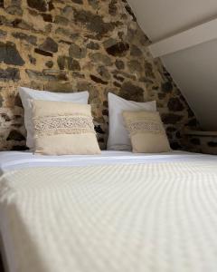 1 cama blanca con almohadas y pared de piedra en Le Moulin de Blanchelande, en Neufmesnil 6 fotos más