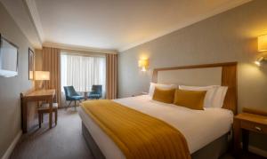 a hotel room with a bed and a desk and chairs at Salthill Hotel in Galway