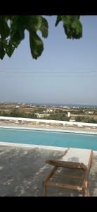 um banco de madeira ao lado de uma piscina em Aegean Queen Villas em Naousa