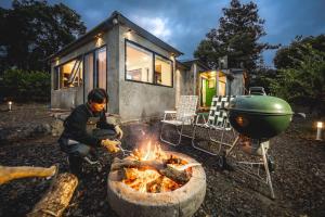 a man cooking food over a fire in front of a house at Pet-friendly camping theme house anseongcamp96 by dazayo in Seogwipo