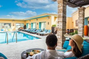 a man and woman sitting on a couch next to a swimming pool at Hotel Contessa - Suites on the Riverwalk in San Antonio