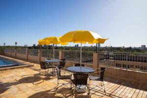 two tables and chairs with umbrellas on a balcony at Rede Andrade Mirante in Foz do Iguaçu