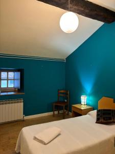 um quarto azul com uma cama e uma cadeira em Zubietako Ostatua em Zubieta