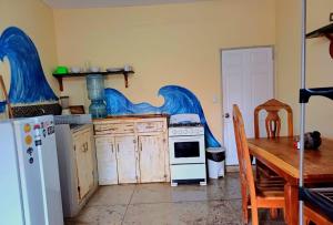 a kitchen with a table and a stove and a refrigerator at Hostel Rossy in San Juan del Sur
