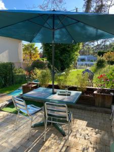 a table and chairs under an umbrella on a patio at Dune et Terrasse in Merville-Franceville-Plage