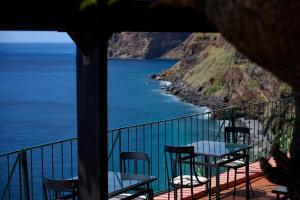 uma varanda com mesas e cadeiras e o oceano em Inn & Art Madeira no Caniço