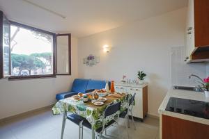 uma cozinha com uma mesa com cadeiras e uma sala de jantar em Pineta Azzurra em Marina di Grosseto