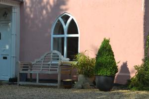 un banco frente a un edificio rosa con ventana en The Cottage Guest House en Bishops Stortford