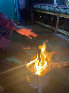 a person is warming their hands over a fire at Hotel PENTOZ - Charring Cross, Ooty in Ooty