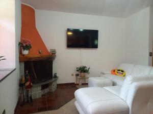 a living room with a white couch and a tv at LA CASETTA DELLE NUVOLE in Mazzo di Valtellina