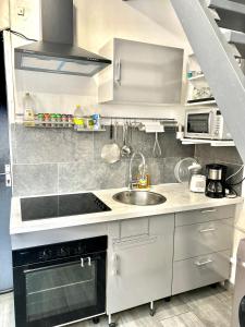 Una cocina blanca con fregadero y estufa. en Appart City, en Fort-de-France