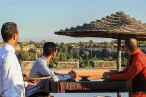 Un gruppo di tre uomini seduti a un tavolo di Riad Golf Stinia a Meknès