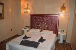 a bedroom with a bed with two black towels on it at Riad Golf Stinia in Meknès