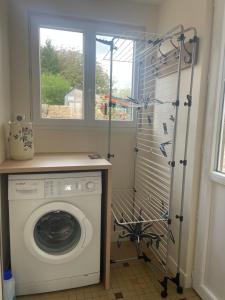 een wasruimte met een wasmachine en een raam bij -Les Petites Planches- Gîte Familial entre Terre & Mer in La Haye-Pesnel
