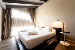 a bedroom with a large white bed with a window at Neko Boutique Hotel in Cagliari