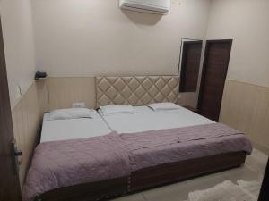 een slaapkamer met een groot bed met witte lakens bij Rk Lodge in Amritsar