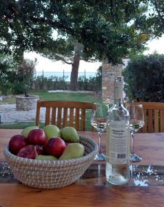 - un bol de pommes et une bouteille de vin sur une table dans l'établissement Varkospito, à Ierápetra