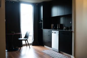 a kitchen with black cabinets and a table and a chair at Central Charming Studio Apartment in Jerusalem in Jerusalem