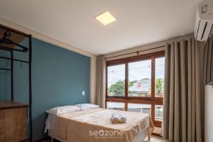 a bedroom with a bed and a large window at CPR - Apartamentos a 200m da praia com Piscina in Marau