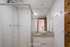 a bathroom with a glass shower and a sink at CPR - Apartamentos a 200m da praia com Piscina in Marau