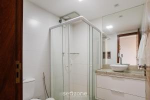 a bathroom with a glass shower and a sink at CPR - Apartamentos a 200m da praia com Piscina in Marau