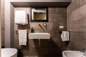 a bathroom with a sink and a toilet and a mirror at Neko Boutique Hotel in Cagliari