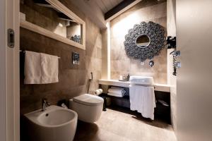 uma casa de banho com um lavatório, um WC e um espelho. em Neko Boutique Hotel em Cagliari
